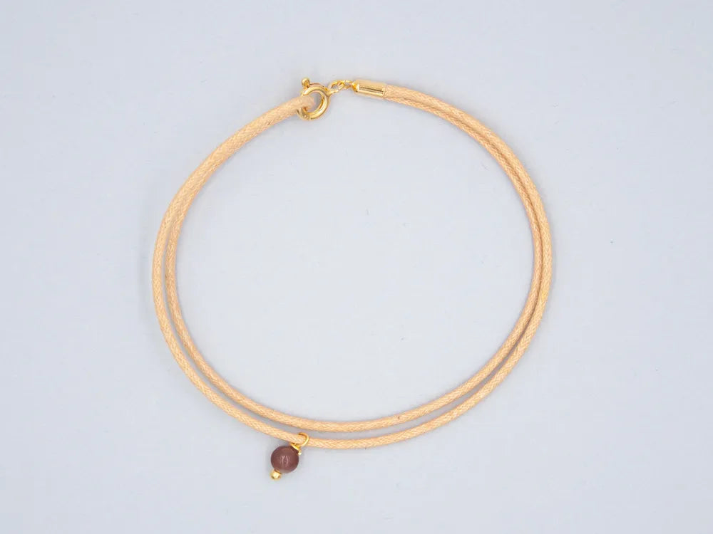 Armband naturfarben aus gewachster Baumwollkordel mit runder Steinperle Aventurin und goldenem Verschluss vor weissem Hintergrund