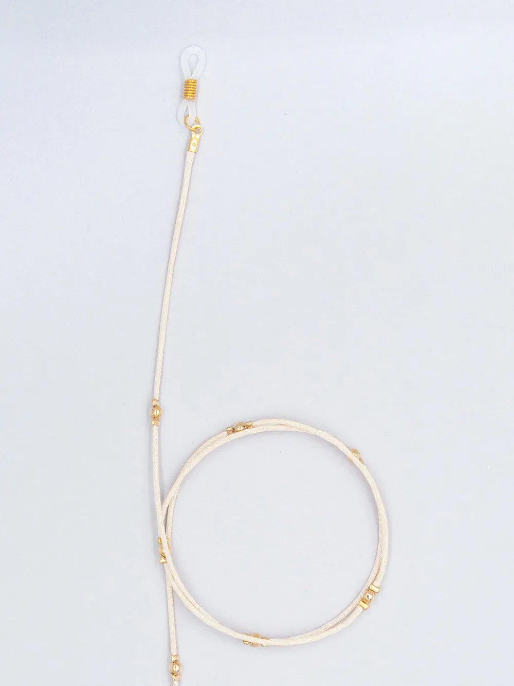Brillenband crème aus gewachster Baumwollkordel in 1,5 mm Dicke mit goldenen Perlen und Gummihalterung auf weissem Hintergrund