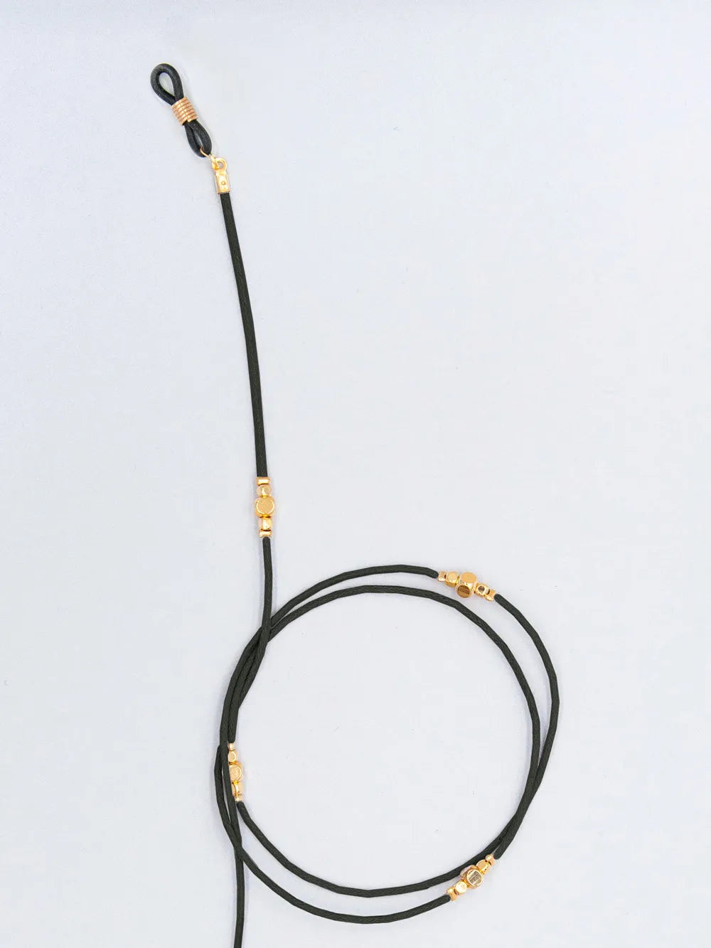 Brillenband schwarz aus gewachster Baumwollkordel in 1,5 mm Dicke mit goldenen Perlen und Gummihalterung auf weissem Hintergrund