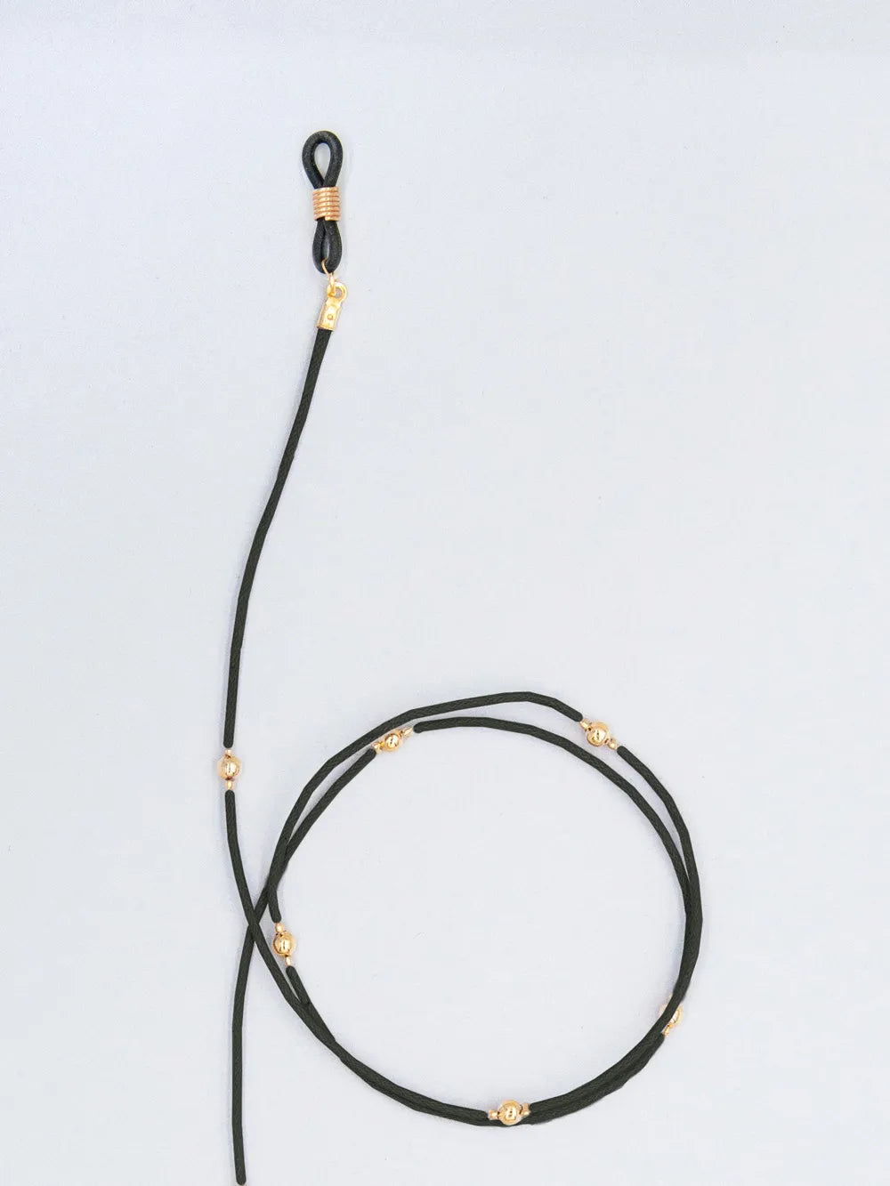 Brillenband schwarz aus gewachster Baumwollkordel in 1,5 mm Dicke mit goldenen Perlen und Gummihalterung auf weissem Hintergrund