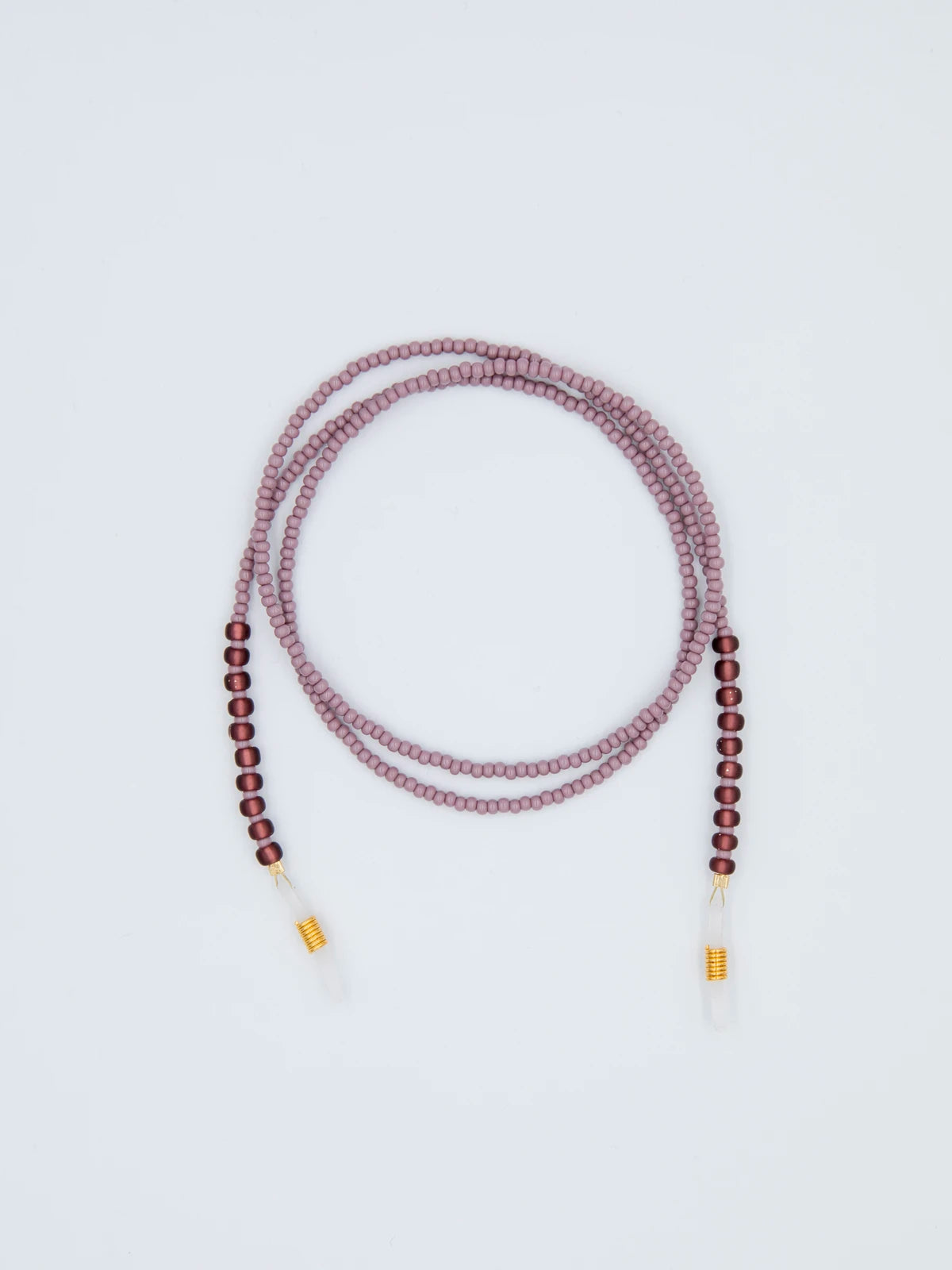 Brillenband aus feinen mauve farbenen und grösseren lila farbenen Glasperlen mit transparenten Brillengummis auf hellgrauem Hintergrund