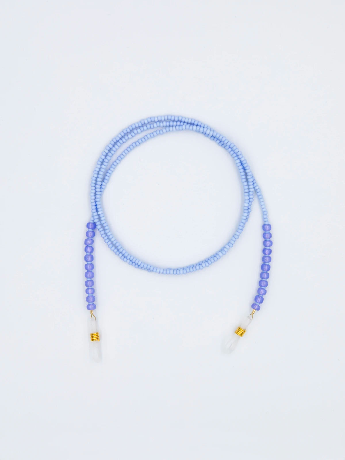 Brillenband aus feinen hellblauen und grösseren violettblauen Glasperlen mit transparenten Brillengummis auf hellgrauem Hintergrund