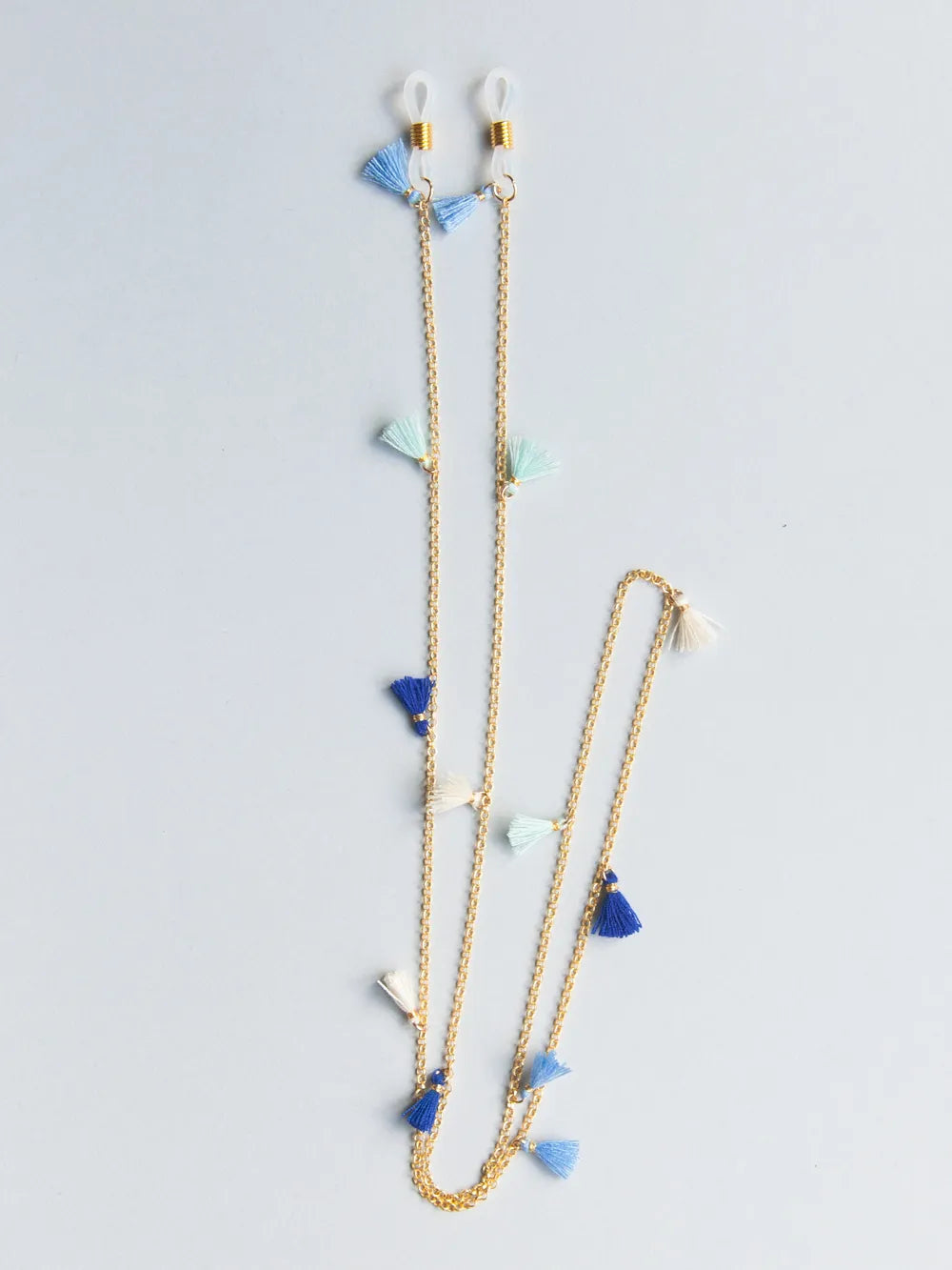 Brillenband aus feiner goldener Kette mit hellblauen, trükisen, weissen und dunkelblauen Quasten auf weissem Hintergrund
