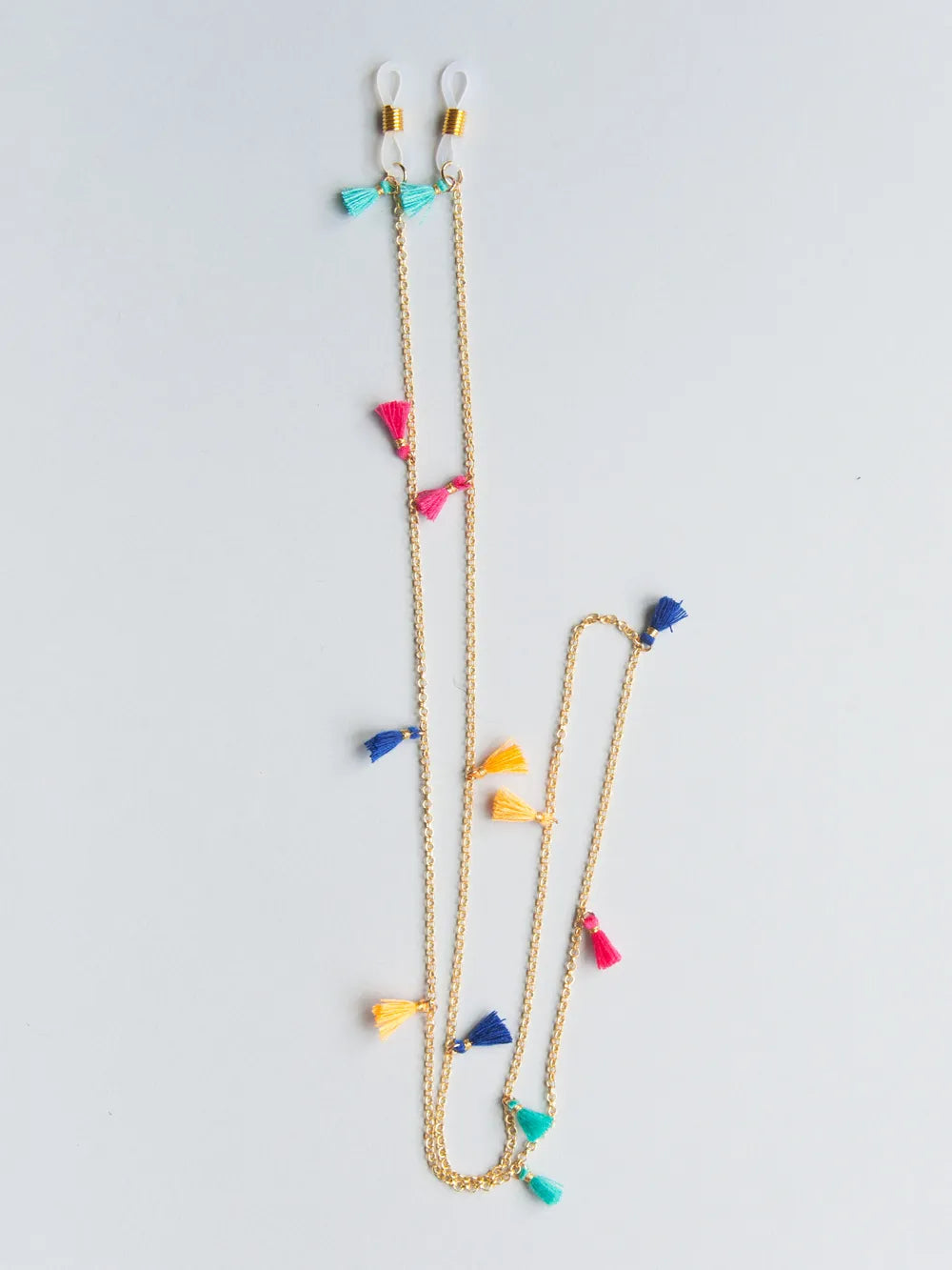 Brillenband aus feiner goldener Kette mit türkisen, pinken, dunkelblauen und gelben Quasten auf weissem Hintergrund
