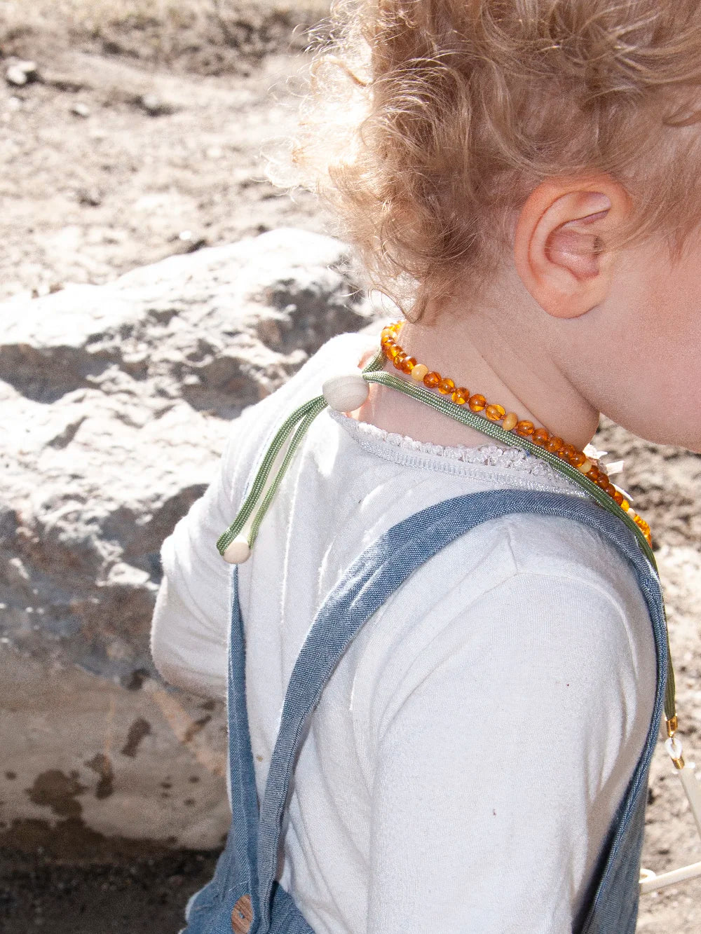 Seitliche Ansicht eines Kinderrrückens mit hellgrünem Brillenband um den Hals, mit Holzperlen in der Grösse verstellt