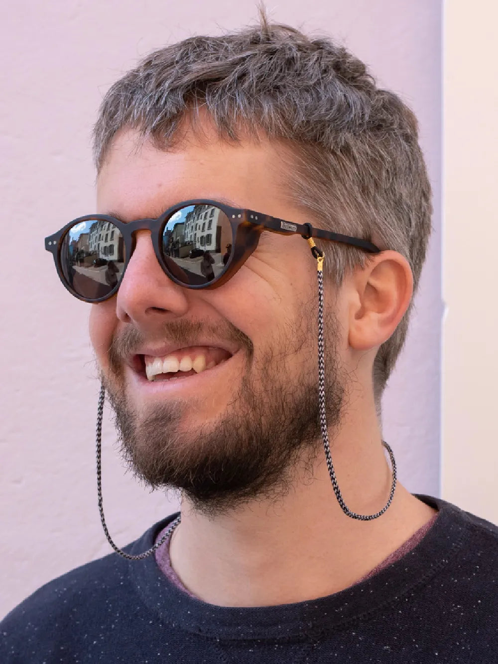 Person mit grauen Haaren und Sonnenbrille mit schwarz-weissem Brillenband