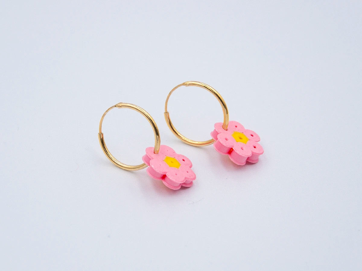 Zwei goldene Creolen mit Blume aus rosa Bügelperlen als Anhänger auf weissem Hintergrund