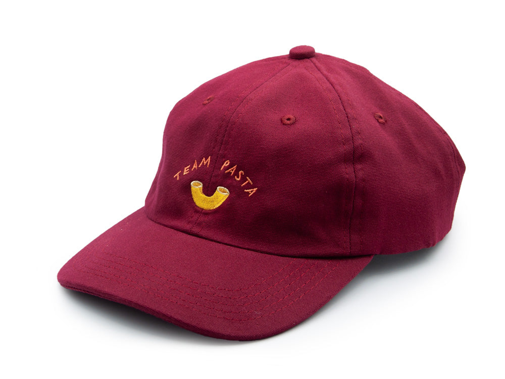 Weinrotes Dad Cap mit der Stickerei Team Pasta und einem ebenfalls gestickten Hörnli auch weissem Hintergrund