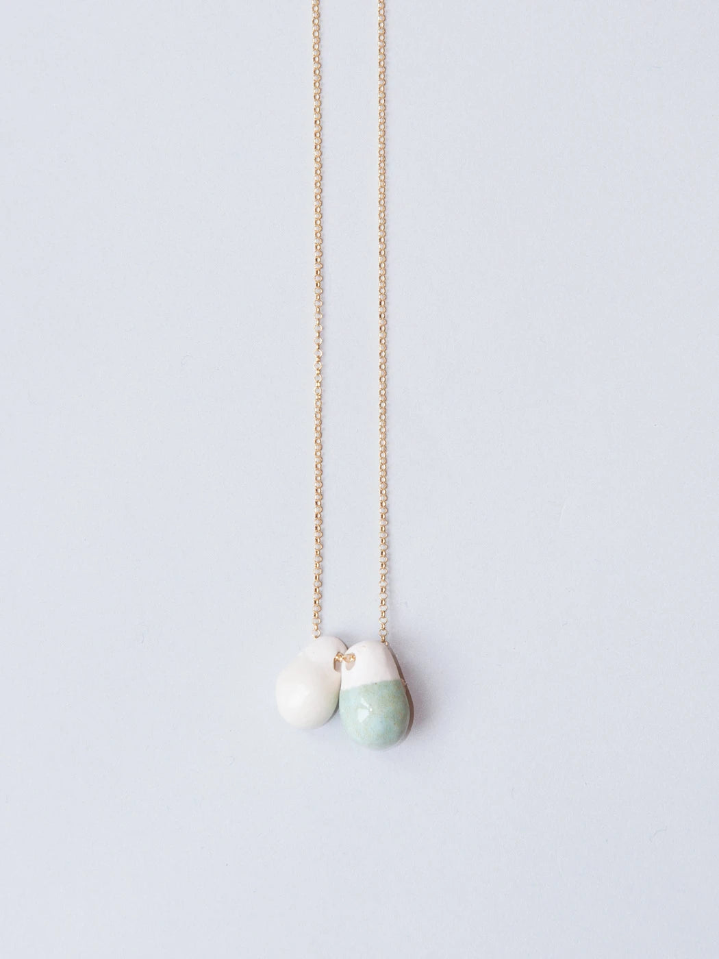 Goldene feine Kette mit zwei tropfenförmigen Porzellananhängern weiss und mint auf weissem Hintergrund