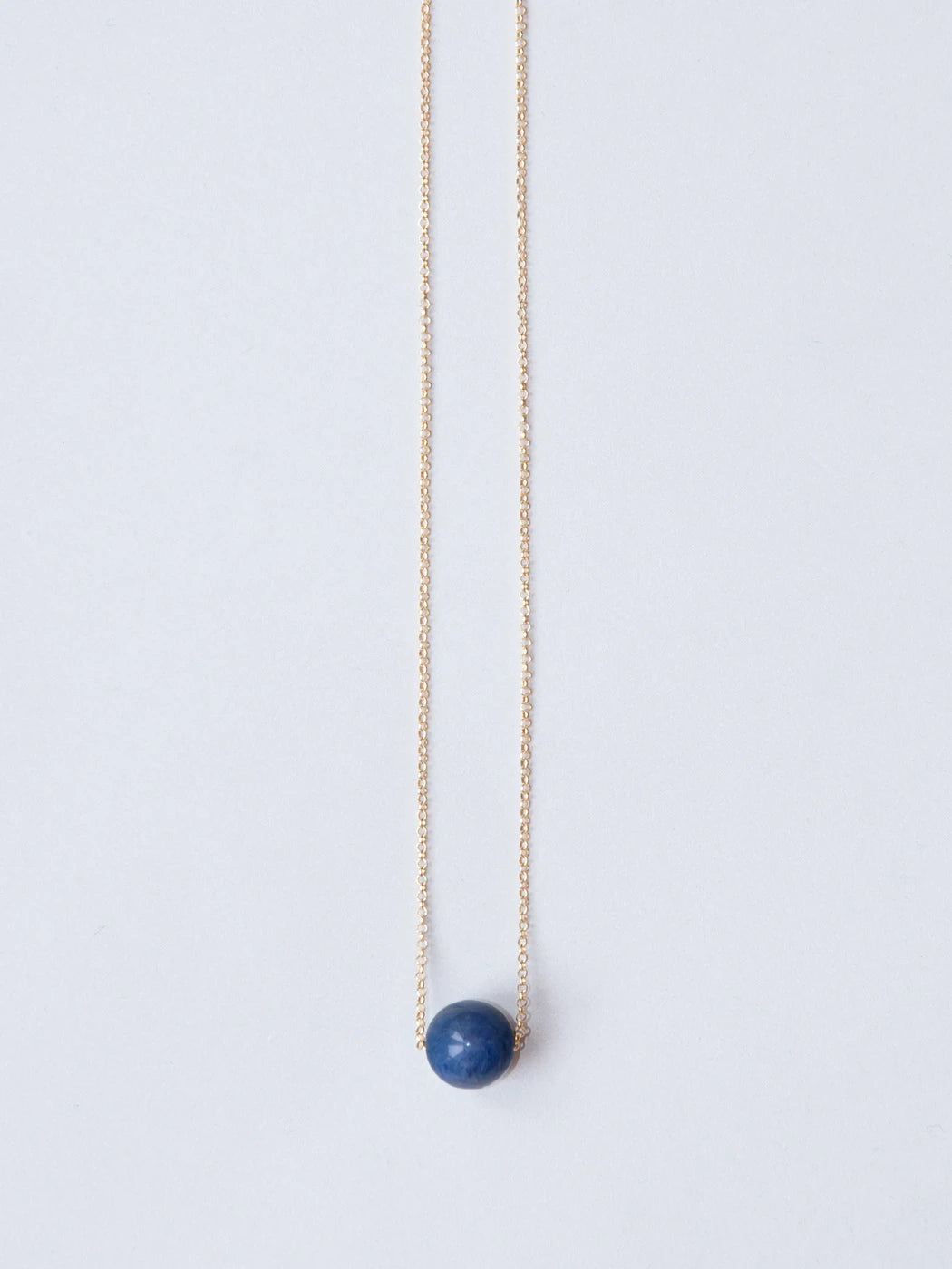 Goldene feine Kette mit Steinperle blau auf weissem Hintergrund