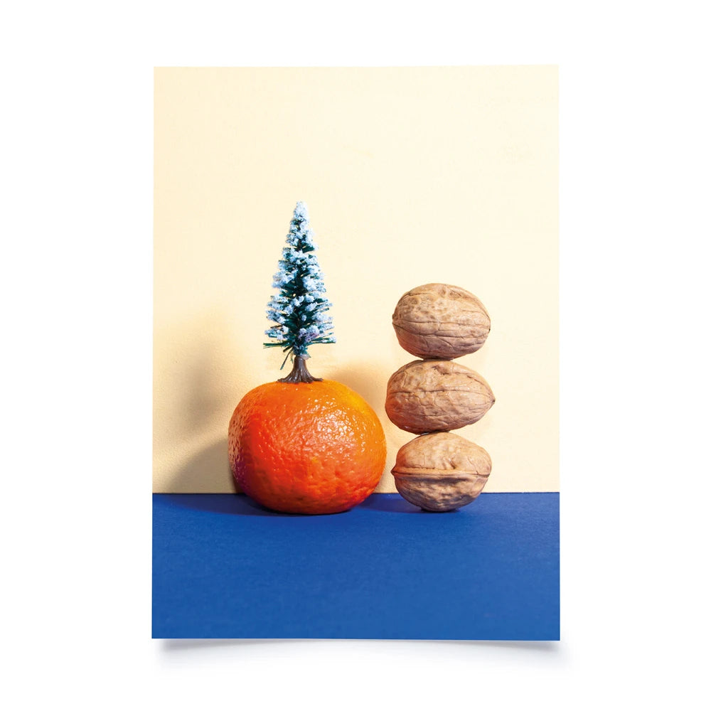 Postkarte mit Farbflächen in creme und blau als Hintergrund, davor eine Mandarine, darauf eine Plastiktanne und daneben drei Walnüsse