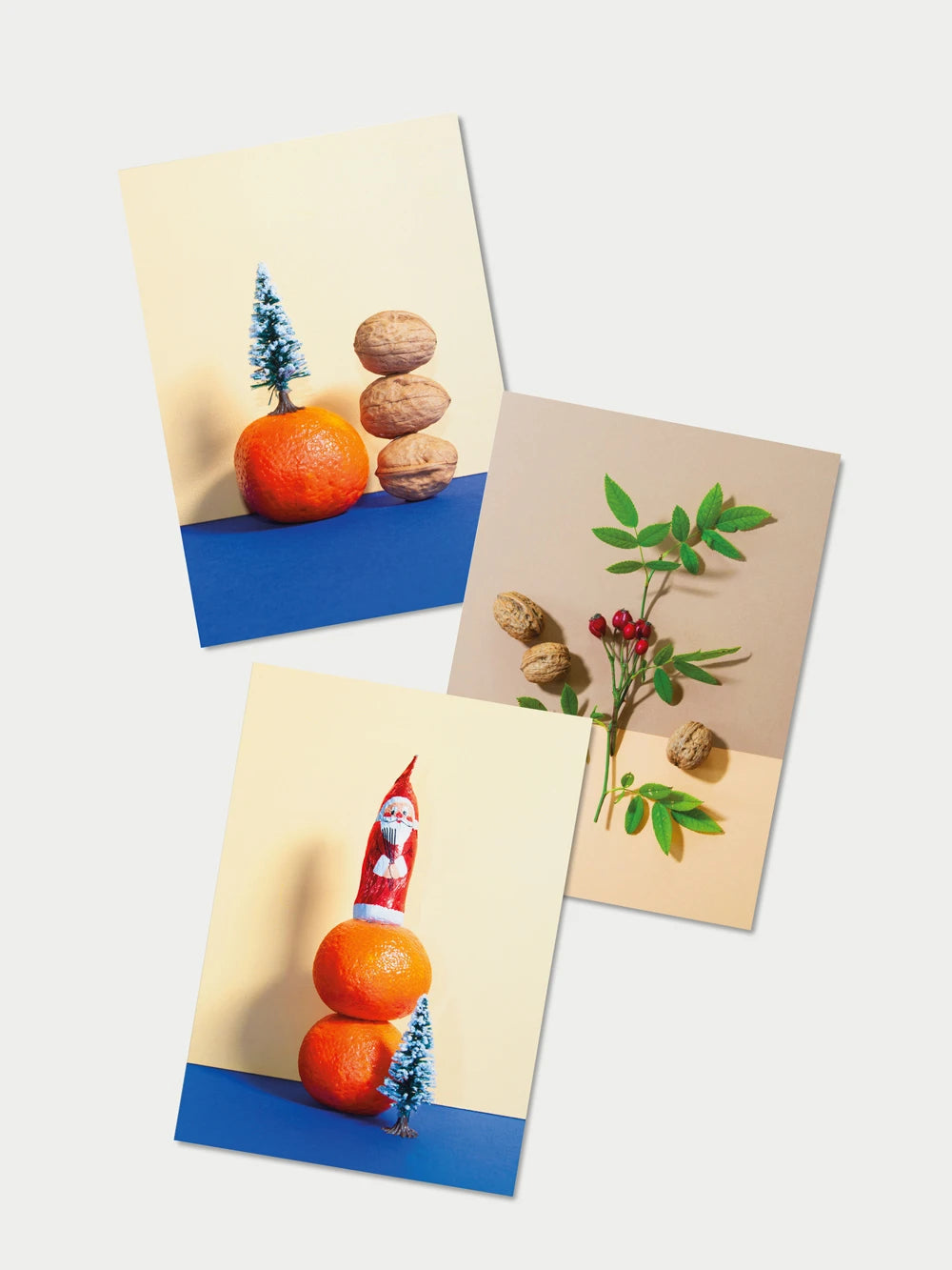 Drei Postkarten auf weissem Hintergrund.
Fotosujets mit Mandarinen, Plastiktannenbaum, Wallnüssen, Hagenbutten und Schokosamichlaus