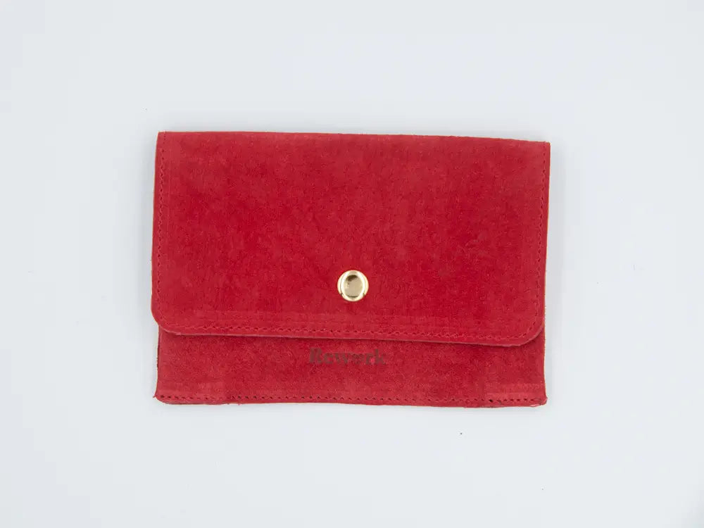 Rotes Lederportemonnaie mit goldenem Druckknopf auf weissem Hintergrund