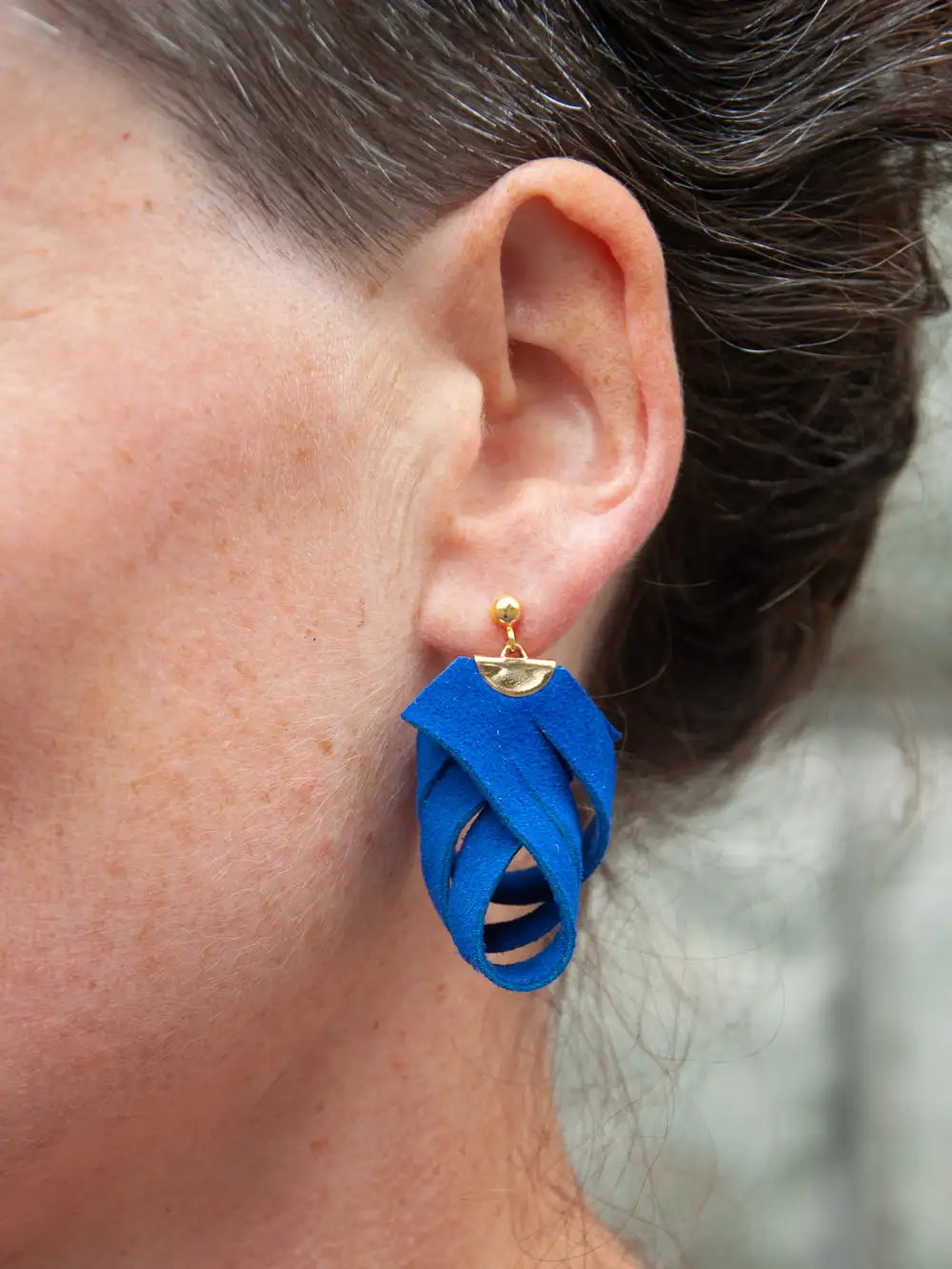 Detailansicht eines Ohrs mit einem Ohrhänger aus blauem Recycling Leder