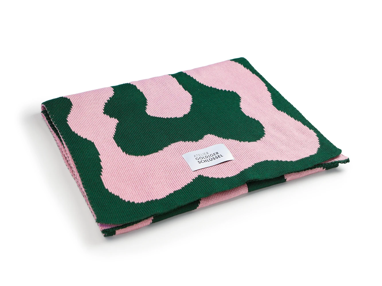 Grün rosa gemusterter Jaquard Schal liegt gefaltet auf weissem Untergrund.