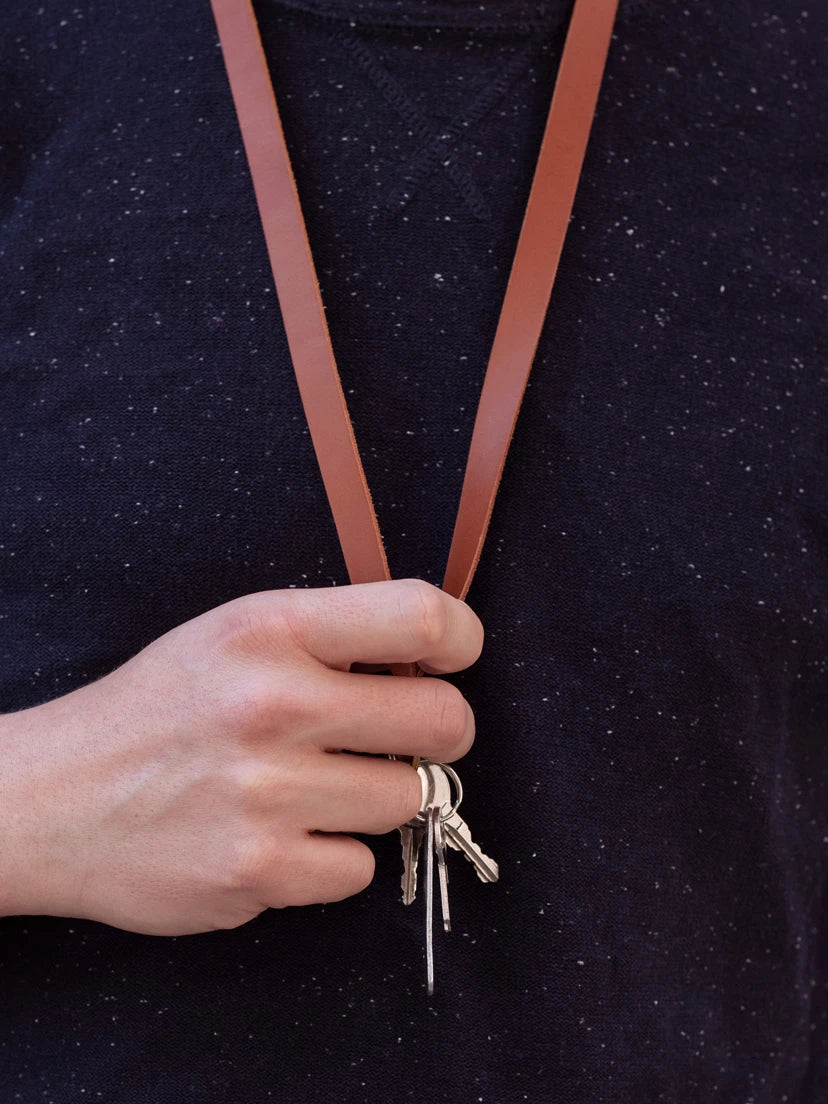 Hand greift an ein braunes Lederschlüsselband