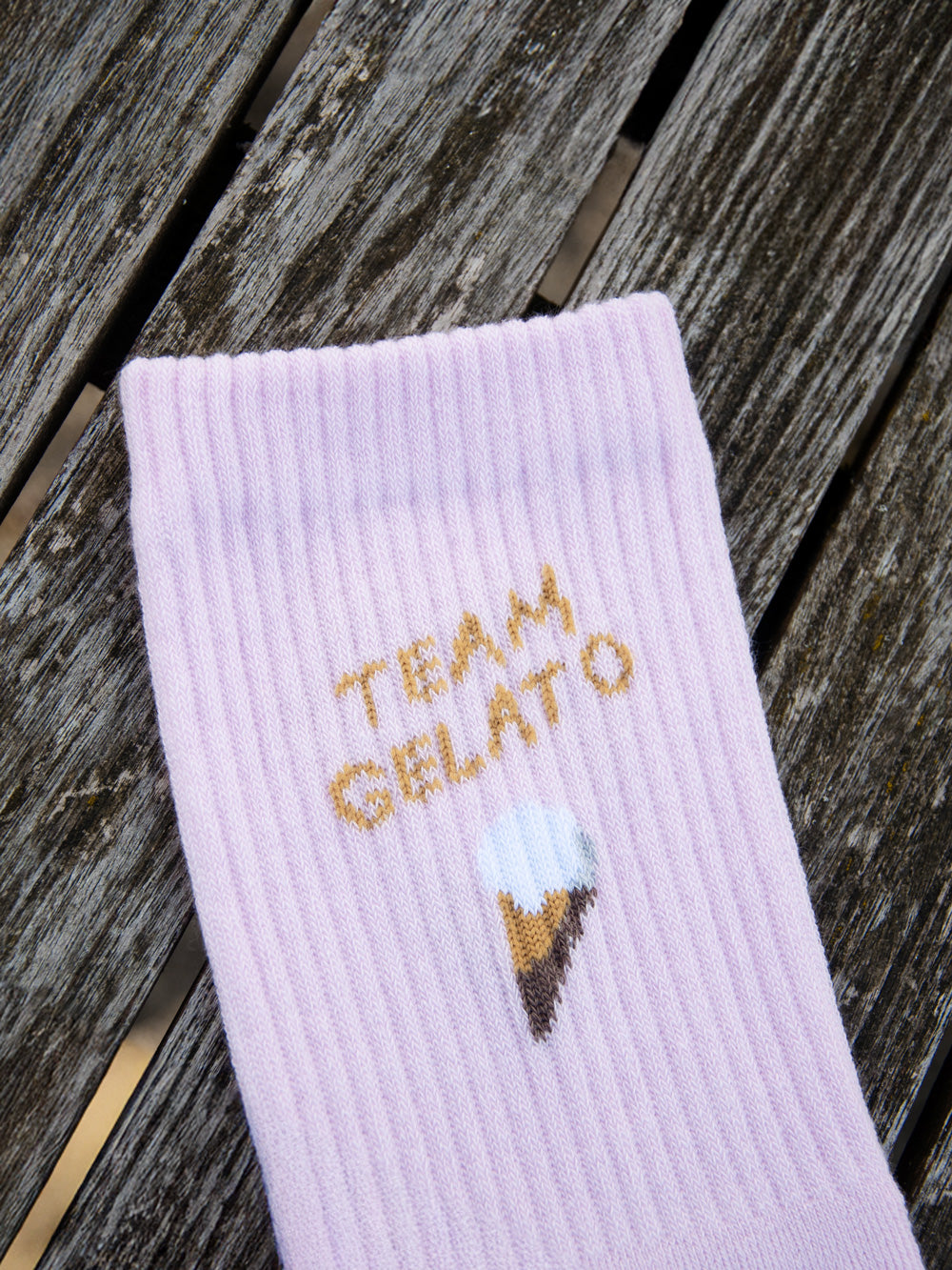 Detail von rosafarbenen Sportsocken von Atelier Goldiger Schlüssel mit dem Design Team Gelato aus Bio-Baumwolle auf holzigem Untergrund