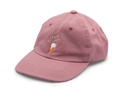 Rosa farbenes Dad Cap aus Bio-Baumwolle mit der beigen Stickerei Team Gelato und einem ebenfalls gestickten Eis auf weissem Hintergrund