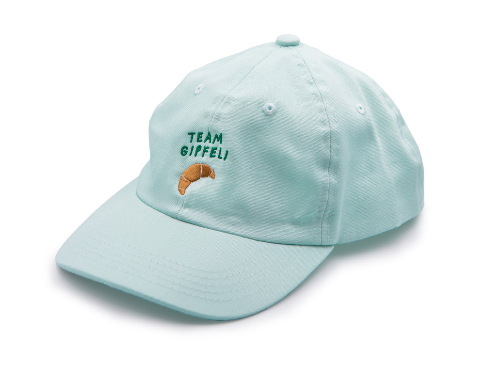 Mint farbenes Cap mit grünem gesticktem Schriftzug Team Gipfeli und einem gestickten Croissant auf weissem Hintergrund.