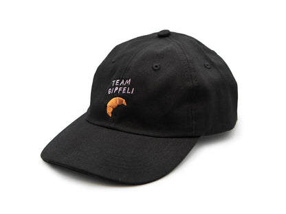 Schwarzes Cap mit grünem gesticktem Schriftzug Team Gipfeli und einem gestickten Croissant auf weissem Hintergrund.