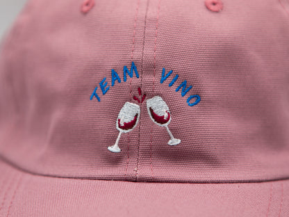 Detailaufnahme einer Stickerei mit dem Schriftzug Team Vino und zwei gestickten Weingläsern auf rosa farbenem Stoff