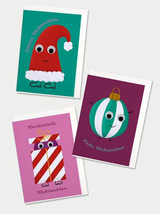 Drei bunte Weihnachtskarten mit Illustrationen einer Nikolausmütze, einer gestreiften Christbaumkugel und einem gestreiften Geschenk. Auf allen Karten sind Wackelaugen auf die Sujets geklebt.