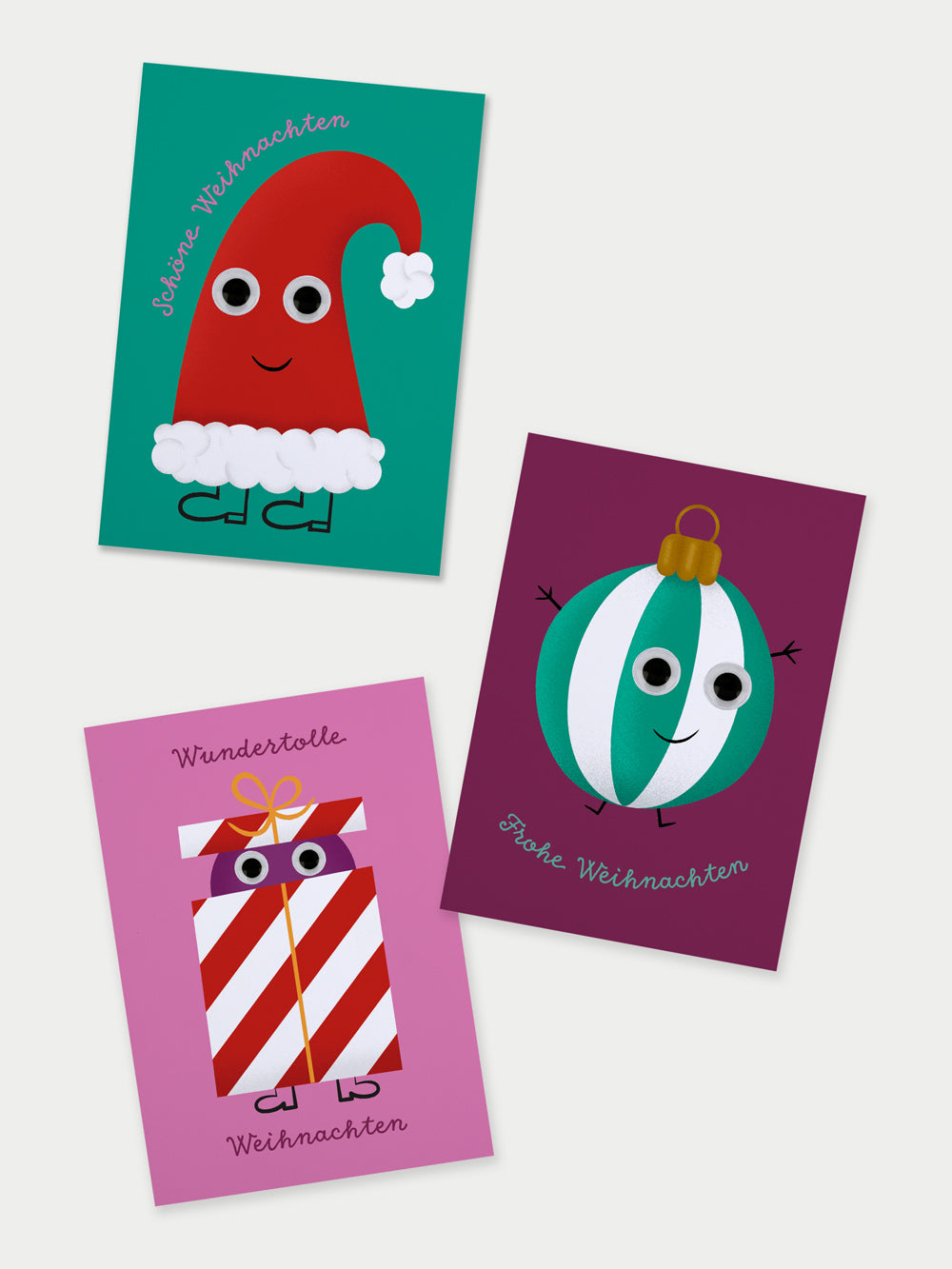 Drei bunte Weihnachtskarten mit Illustrationen einer Nikolausmütze, einer gestreiften Christbaumkugel und einem gestreiften Geschenk. Auf allen Karten sind Wackelaugen auf die Sujets geklebt.