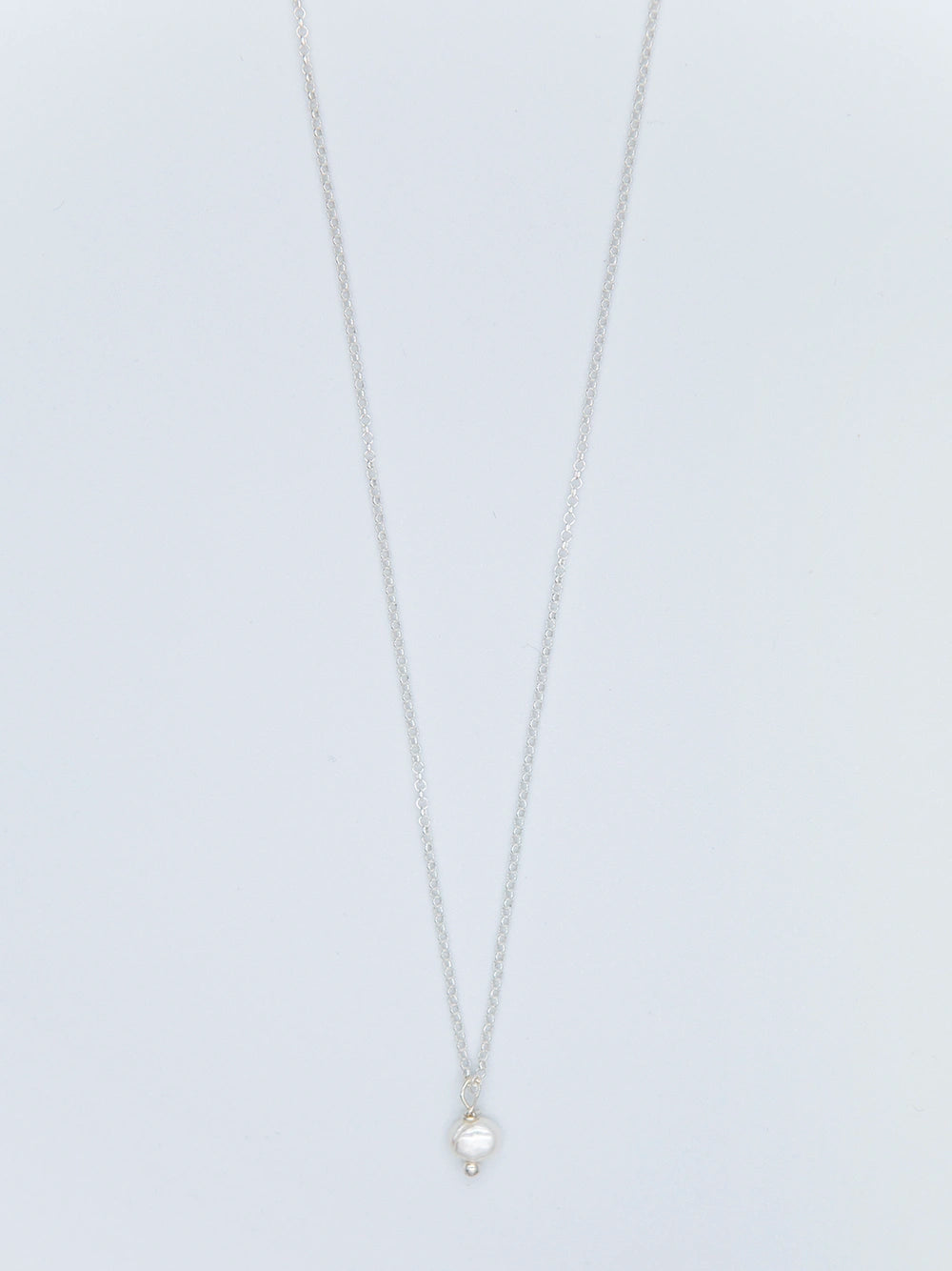 Halskette aus Sterlingsilber mit Anhänger aus Süsswasserperle auf hellgrauem Untergrund.