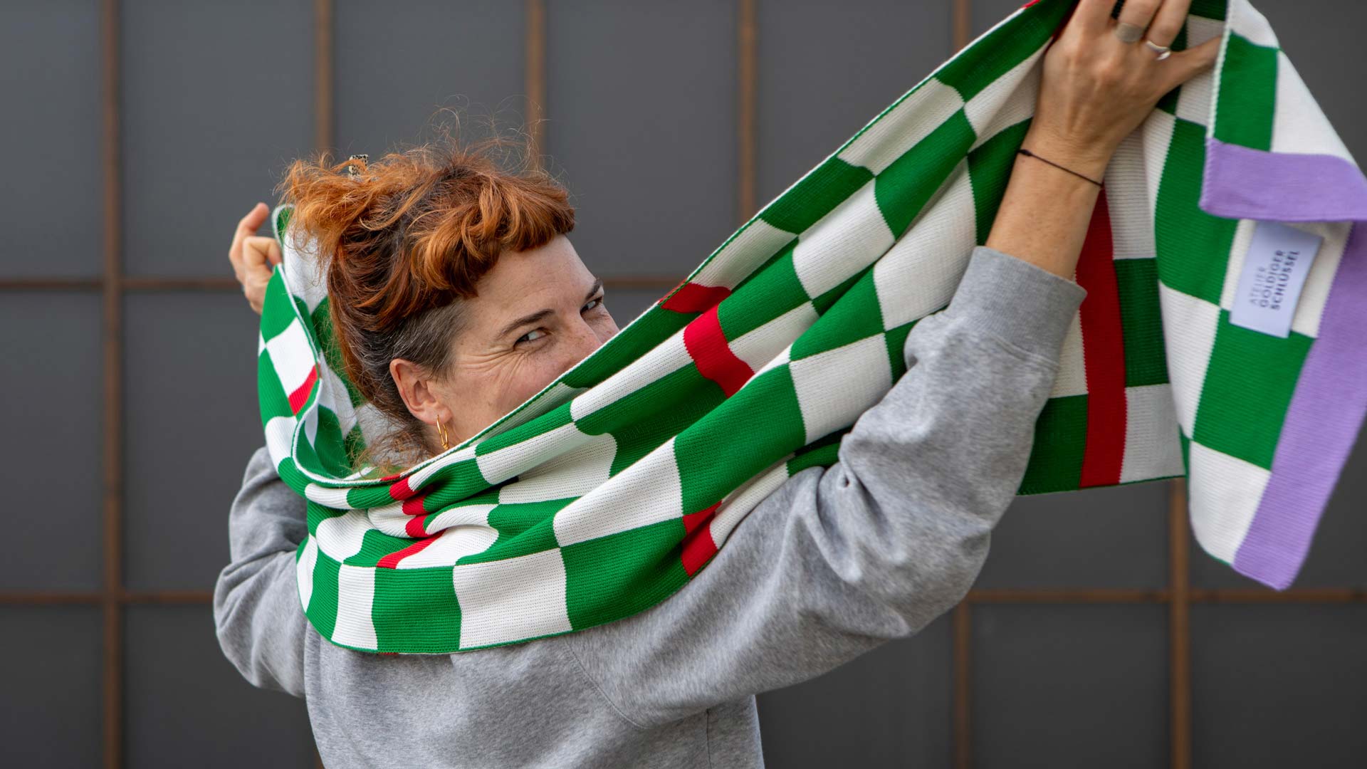 Frau mit orangen Haaren trägt grün-weiss karierten Schal aus Bio-Baumwolle