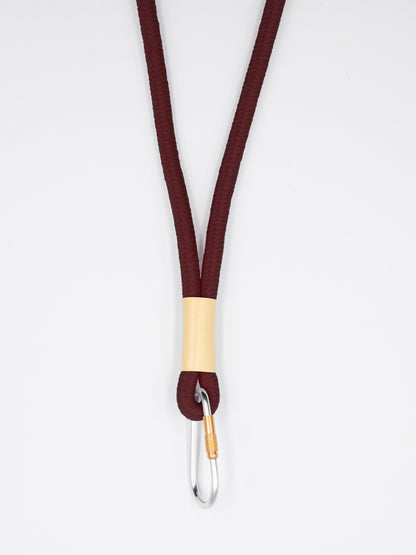 Braunes Schlüsselband aus Baumwollkordel mit silbernem Karabiner auf weissem Untergrund.