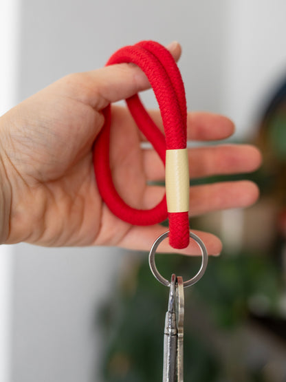 Detailaufnahme einer Hand die eine Schlüsselschlaufe aus roter Kordel mit zwei Schlüsseln hält