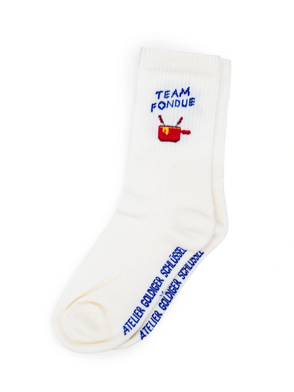 Weisse Sportsocken mit dem blauen Schriftzug Team Fondue sowie einem roten Caquelon darauf, auf weissem Hintergrund